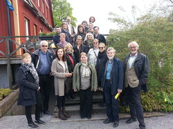 Gruppfoto med deltagare på en trappa vid en röd byggnad.