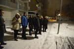 Grupp människor utomhus med byggnad i bakgrunden. Foto.