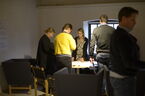 Två fåtöljer med en grupp människor i bakgrunden. Foto.